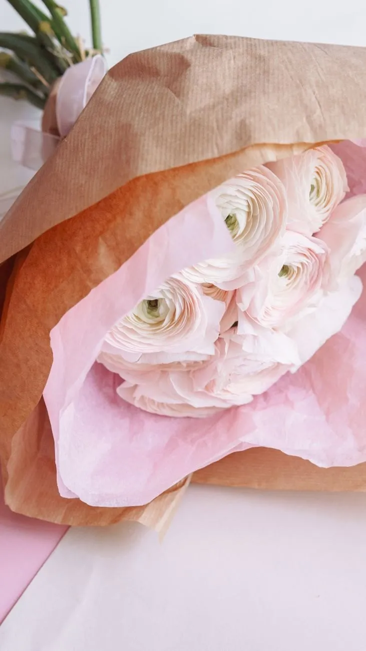Blush and white ranunculus wrapped in kraft and pink tissue